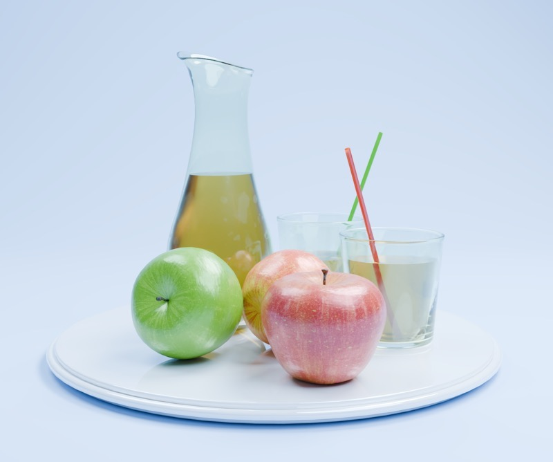 Juice carafe, glasses and apples under cool lighting.